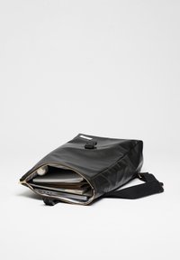 Schwarze Laptoptasche aus glattem Material. Rechteckige Form, Reißverschlussverschluss und ein einzelner verstellbarer Tragegurt. Enthält Unterlagen und einen Laptop.