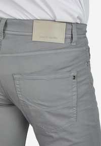 Grijze broek met een soepele afwerking, voorzien van een rechthoekig label met de markering "pierre cardin" op de achterkant. Stikdetails zichtbaar.
