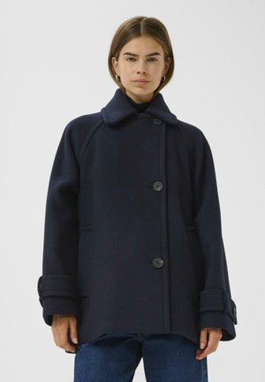 Navy wool coat with a notched collar, button closure, and side pockets. Features wide, rolled cuffs and a relaxed fit design.