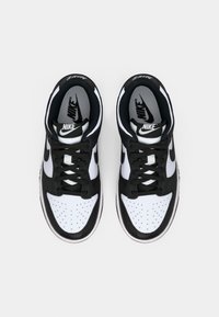 Zwart-witte Nike-sneakers met een bovenwerk van glad leer, geperforeerde neus, platte zwarte veters en zwart-witte binnenzolen met merkopdruk.