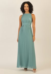 Tanzanite-farbene Maxikleid mit Falten, einem taillierten Bund und hohem Ausschnitt. Der Stoff ist glatt mit einer fließenden Silhouette. Silberne High Heels.