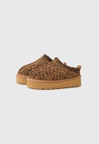 Leopardprint instappers van bruin suède, met een rubberen zool en zwarte patroonaccenten bij de opening.
