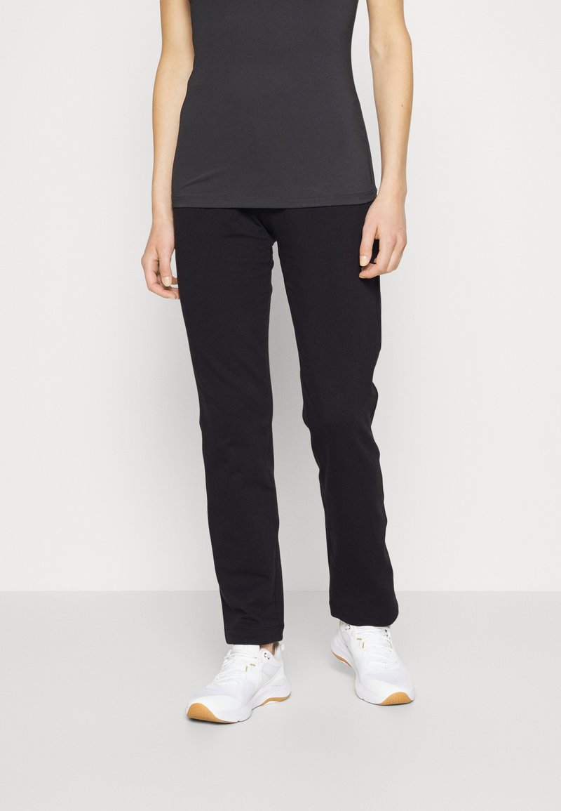 Svarta stretchbyxor med slim fit, med en slät midjeresår. I kombination med en åtsittande mörk topp och vita sneakers. Slät tygkänsla.