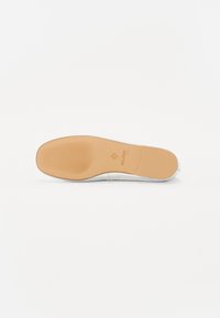 Vit sneakersula med en beige gummiundersida, med texturerade spår och en präglad logotyp. Slät övre kant med minimal design.