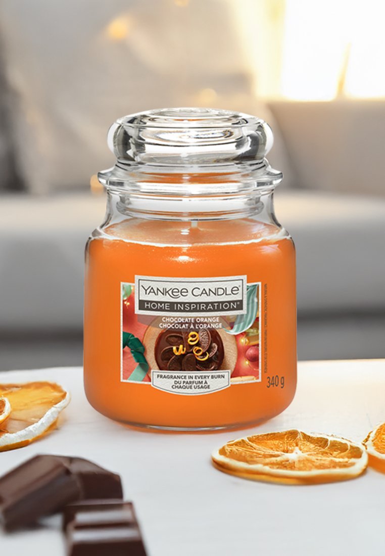Yankee Candle in einem klaren Glasgefäß mit einem runden Deckel, gefüllt mit orangem Wachs. Das Etikett zeigt Grafiken von Schokolade und Orange, 340 g.