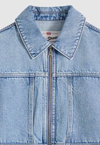 Φωτεινό γαλάζιο τζιν μπουφάν με δομημένο γιακά, φερμουάρ μπροστά και δύο τσέπες στο στήθος. Διαθέτ ει ραμμένες ραφές και κλασική γραμμή.