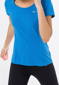 Modré sportovní tričko z síťoviny s kulatým výstřihem, krátkými rukávy a malým stříbrným logem Nike na levé straně hrudi.