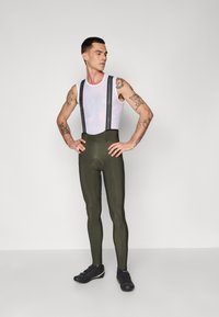 Cuissards de cyclisme pour hommes en olive avec des bretelles noires, offrant une coupe ajustée, en matériau Lycra texturé, et un rembourrage en chamois renforcé.