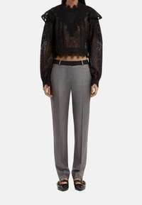 Zwart kanten cropped top met pofmouwen en geschulpte randen, gecombineerd met grijze op maat gemaakte broeken. Het schoeisel heeft een geweven ontwerp.