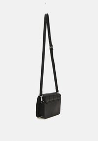 Bolso bandolera negro hecho de cuero texturizado, con una tapa frontal acolchada, correa ajustable y detalles en hardware plateado.