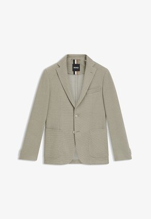 Vaaleanharmaa bleiseri, joka on valmistettu teksturoidusta kankaasta. Ominaisuuksiin kuuluu lovelliset läpät, kaksi etutaskua ja yksi rintatasku nappilukoilla.