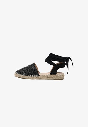 Sandalia espadrille negra con suela de yute trenzado, punta cerrada y lazos para atar alrededor del tobillo, mostrada de perfil sobre fondo blanco.