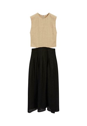 Top beige senza maniche con collo alto e finitura texturizzata, abbinato a una gonna nera a campana con pieghe e orlo fluente.