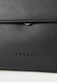 Musta nahkainen laukku, jossa on sileä pinta, varustettuna läppäkiinnityksellä ja kohokuvioidulla brändinimellä "bugatti" edessä.