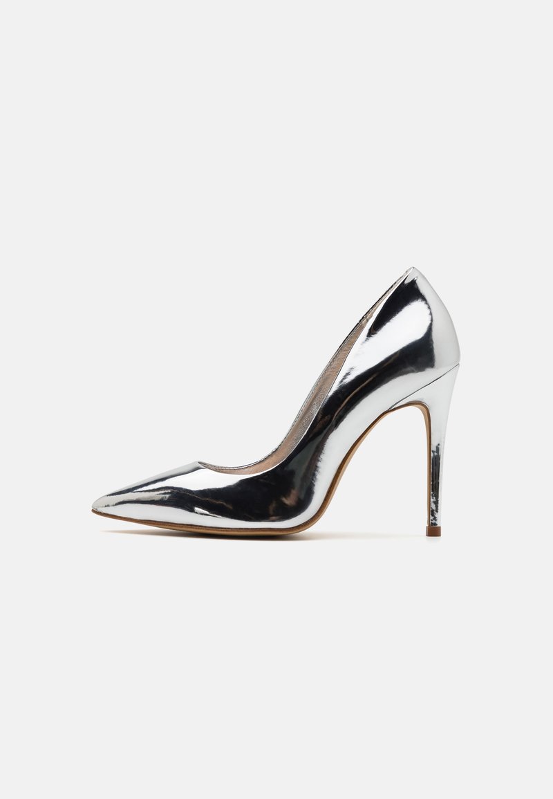 Escarpin à talon haut argenté brillant avec bout pointu et talon aiguille fin sur fond blanc uni.
