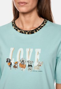 Mint green t-shirt with a leopard print collar, featuring a graphic print of various dog illustrations and the word "LOVE" in white.