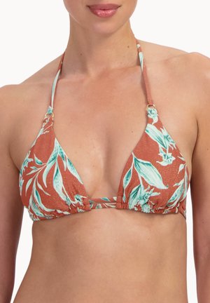 Kobieta nosząca rustykalny bikini top w kwiatowy wzór z niebiesko-białymi liśćmi oraz paseczki na szyję.