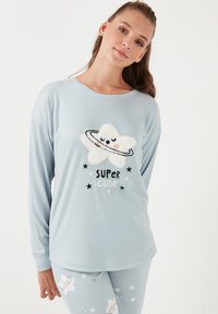 Svijetloplavi pidžama set s dugim rukavima koji ima pahuljasti grafički prikaz zvijezde i tekst "SUPER CUTE" uz otiske zvijezda i planeta na hlačama.