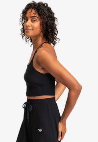 Svart ribbad crop top med tunna remmar, i kombination med svarta byxor som har dragsko och liten broderad hjärtlogga på höften.