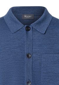 Kragen-Poloshirt in Blau. Hergestellt aus strukturiertem Stoff mit einem Kragen, drei schwarzen Knöpfen und einer Brusttasche.