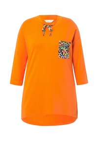 Camiseta de algodón naranja con mangas tres cuartos, cuello redondo, que presenta un bolsillo con estampado de leopardo y acentos coloridos.