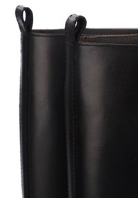 Stivali alla caviglia in pelle nera con texture liscia, cuciture verticali e linguette ad anello nella parte superiore per una facile calzata. Design minimalista.