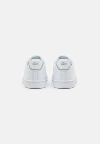 Hvite lær sneakers med glatt tekstur, bak-logo, polstrede krager og hvite gummisåler. Klassisk low-top design med sømdetaljer.