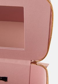 Estuche rosa con cremallera, con un exterior de tela suave y un interior liso, que cuenta con una ventana rectangular y una cremallera dorada.