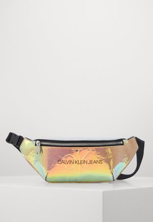 Holograficzna nerka Calvin Klein Jeans z czarnym zamkiem błyskawicznym i regulowanym czarnym paskiem na białej powierzchni i tle.