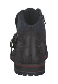 Bruine leren boot met een gebreide manchet, ronde neus en gestructureerd oppervlak. Heeft een zijrits en een robuuste zool met een rode accent.