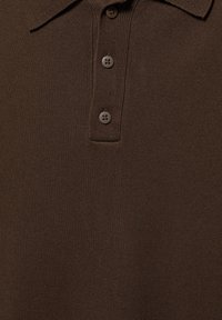 Polo marron en maille avec trois boutons et un col, montrant la texture détaillée du tissu.
