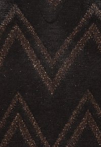 Tessuto nero con un motivo a zigzag, caratterizzato da accenti di filo metallico bronzo che creano un aspetto strutturato e scintillante.