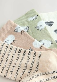 Vier paar sokken: roze met schapen, groen met schapen, wit met zwarte harten en gestreept beige met zwarte patronen. Zachte, gebreide textuur.