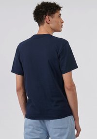 T-shirt en coton bleu marine à manches courtes, col rond, avec un dos uni. Le tissu semble lisse, avec une coupe décontractée.