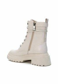 Stivaletti beige alla caviglia con suola spessa, realizzati in pelle liscia. Presentano lacci frontali, chiusura con zip laterale e un branding minimalista sul tallone.
