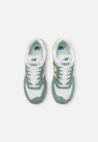 Gröna och vita mockasneakers har en texturerad ovandel, platta snören, vadderad krage och en framträdande "N"-logotyp på sidan.