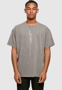 Gray oversized T-shirt in cotton, featuring a round neckline and short sleeves. Front has a white "faith" text design. Textured finish.
