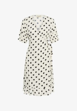 Wikkeljurk in crème stof met zwarte penseelstreek stippen, korte pofmouwen, V-halslijn en een strikdetail in de taille. Uitlopende zoom.