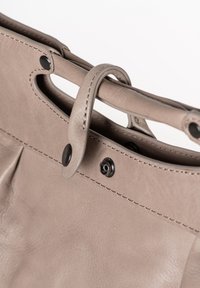 Grijze leren handtas met twee handgrepen, voorzien van een drukknoopsluiting, zichtbare stiksels en een gladde textuur. Centrale plooien nabij de opening.