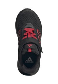 Zapatilla deportiva negra con parte superior de malla, acentos rojos y correa de velcro integrada. Presenta una superficie texturizada y una suela acolchada para mayor comodidad.