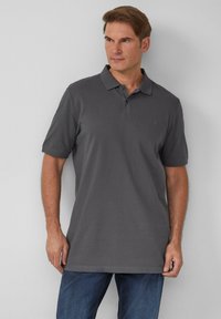 Szara koszulka polo z ribbowym wykończeniem, krótki rękaw i klasyczny kołnierzyk, zestawiona z niebieskimi dżinsami. Prosty design, bez widocznych wzorów.