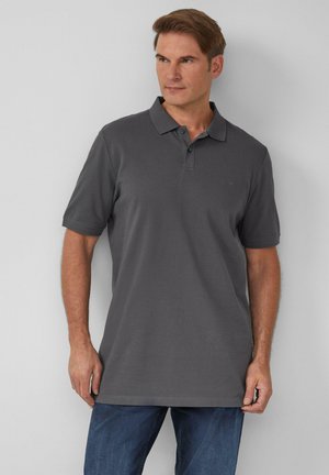 Graues Poloshirt mit gerippter Textur, kurzen Ärmeln und einem klassischen Kragen, kombiniert mit blauen Jeans. Einfaches Design, keine sichtbaren Muster.