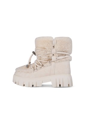 Beige suede ankle boots with faux fur lining, thick rubber sole, and lace-up design. Features decorative straps and metal accents.