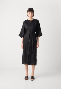 Μαύρο λινό φόρεμα με κουμπιά μπροστά, τρία τέταρτα μανίκια, ζώνη στο ύψος της μέσης και μήκος midi. Απλός σχεδιασμός και υφή.