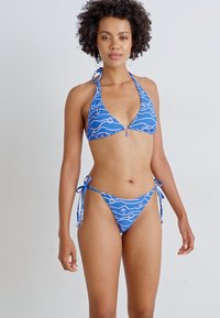Modrý bikiny set s trojuholníkovým halter vrškom so strieborným krúžkom a zodpovedajúcimi spodkami s viazaním na bokoch, oba so vzorom bielych vĺn.