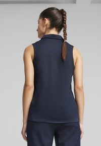 Námořnická modrá polo košile na ramínka s límečkem, hladkou texturou a uvolněným střihem. Obsahuje rovný lem a minimální detaily.