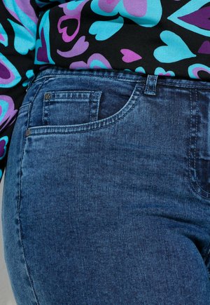 Tumma denimmateriaalinen farkut, joissa on sileä pinta, klassinen viiden taskun malli ja ommeltu vyötärönauhakohta, jossa on hienovarainen kiilto.