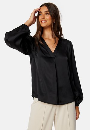 Blusa nera in satin con scollatura a V, maniche voluminose e vestibilità rilassata. Tessuto liscio con una leggera lucentezza e polsini arricciati.