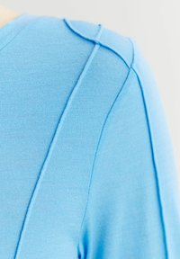 Niebieski, dziany sweter o gładkiej fakturze, z okrągłym dekoltem i subtelnymi detalami szwów wzdłuż ramion i boku.