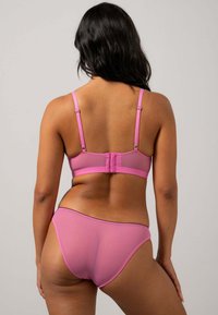 Der pinke BH und die passenden Unterwäsche bestehen aus weichem Material, verfügen über verstellbare Träger und haben ein Netzdesign mit kontrastierenden Kanten.